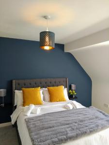 a bed with yellow pillows and a blue wall at Rosies in Clifden