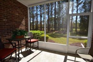 una veranda schermata con tavolo, sedie e una grande finestra di 1113 River Crossing Condo a North Myrtle Beach