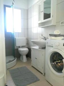 ein Badezimmer mit Waschmaschine und Waschbecken in der Unterkunft Apartment Seashell in Šišan