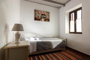 1 dormitorio con 1 cama y 1 mesa con lámpara en Stone House-Athina, en Peletá