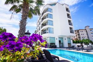 a hotel with a swimming pool and palm trees and purple flowers at Aurasia Sea Side Hotel in Marmaris