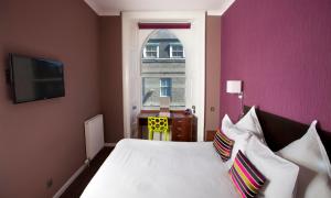 a bedroom with a white bed with a pink wall at Carmelite Hotel in Aberdeen