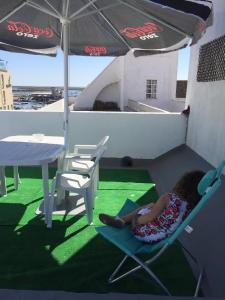 a little girl laying in a chair under an umbrella at Casa Tradicional Algarvia - Rooms in Faro