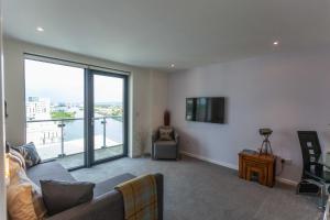 a living room with a couch and a large window at Waterfront West End Apartment in Glasgow