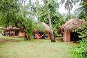 a house with two thatched huts in a forest at Pousada Doze Cabanas in Japaratinga
