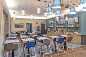 une salle à manger avec des tables et des chaises bleues dans l'établissement The Originals Boutique, Hôtel des Marins, Saint-Malo (Inter-Hotel), à Saint-Malo