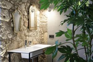 a bathroom with a white sink and a plant at ISONZO SUITES in Siracusa