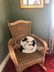 Una almohada de vaca sentada en una mecedora de mimbre en Buttermilk Lodge Guest Accommodation, en Clifden