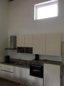 a kitchen with white cabinets and a sink and a window at Ferienwohnung Reh in Bad Rappenau