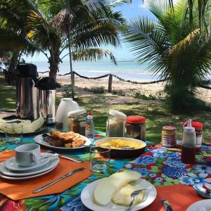a table with plates of food on the beach at Pousada Doze Cabanas in Japaratinga