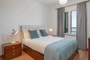 a bedroom with a bed with blue pillows and a window at Garajau III by An Island Apart in Caniço