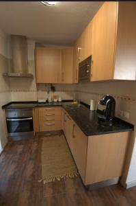 a kitchen with wooden cabinets and a black counter top at Apartamento Sto Estevão in Zambujeira do Mar