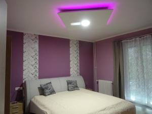 um quarto com uma cama branca e um tecto roxo em Győri úti lakás em Tatabánya