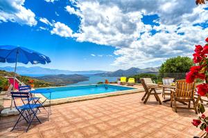 un patio con piscina, sedie, tavolo e ombrellone di Villa Thea a Vrouchas