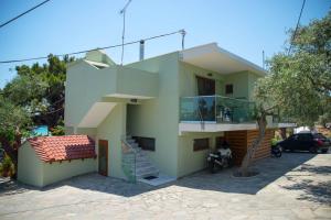una casa verde con una escalera delante de ella en Psili Ammos Seaside Luxury Rooms, en Astris