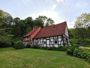 an old house with a red roof on a green field at Ferienhof Ehlers in Hülsede