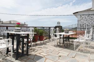 a patio with tables and chairs and a fence at Archontiko Panagoula in Portaria