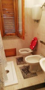 uma casa de banho com um WC com um assento vermelho e um lavatório em "Al Vecchio Studio" em Vibo Valentia
