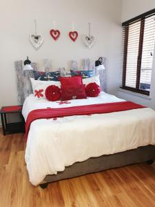 een slaapkamer met een bed met rode kussens en harten aan de muur bij Cabana Del Mar 69 in Amanzimtoti