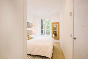 a white bedroom with a bed and a window at PRIM 26 in Donostia-San Sebastián