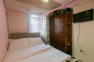 um pequeno quarto com uma cama e uma televisão em Zarita Boutique Hotel em Nairobi