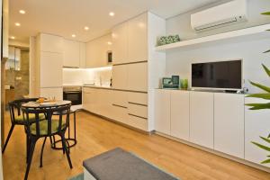 a kitchen with white cabinets and a table and a television at BmyGuest Bruno’s 36 Apartments in Lisbon