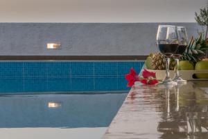 カラマキにあるHoumeli Maisonettes & Apartmentsのプールサイドのテーブルに座ってワインを楽しめます。