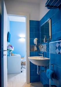 ラ・スペツィアにあるAffittacamere Rosyの青いタイル張りの壁、洗面台付きのバスルーム