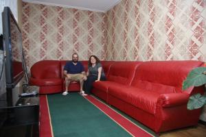 a man and a woman sitting on a red couch at MEDI Guest House in Osh