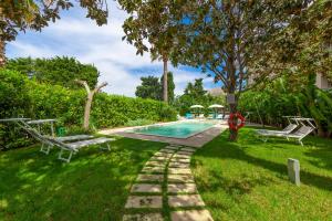 a swimming pool with two benches in a yard at Relais Regina Rosanna in Gallipoli