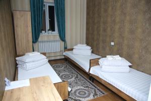 a room with two beds and a wooden table at MEDI Guest House in Osh