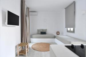 a white living room with a bed and a table at White Blossom in Parikia