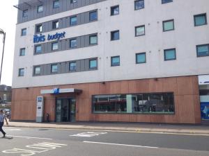 a building on a street with a person walking in front at ibis budget London Hounslow in Hounslow