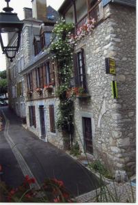 a stone building with flowers on the side of a street at Dolwin in Argelès-Gazost