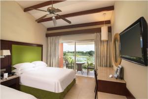 
a hotel room with a bed, tv and a window at Barceló Bávaro Palace All Inclusive in Punta Cana
