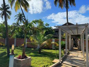 un jardin avec des palmiers et une pergola dans l'établissement Villa San Miguel, à Ouidah