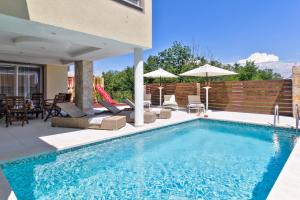 a swimming pool in a backyard with chairs and an umbrella at Istrian Guest House ILLY in Kaštel