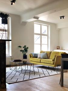 a living room with a yellow couch and a rug at Bed & Boon in Ghent