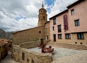 um edifício com uma torre de relógio e uma parede de pedra em Hotel Albanuracín em Albarracín