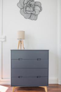 a dresser with a lamp and a flower on a wall at CosyRouen Gare in Rouen