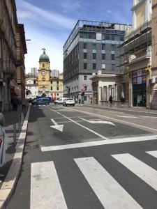 una strada vuota in una città con una torre dell'orologio di Apartman Licia a Fiume (Rijeka)