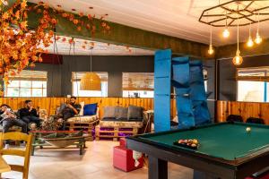 a pool table in a living room with people sitting at Hostel Pioneros del Valle in El Chalten