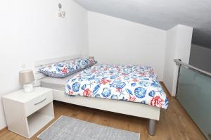 a white bedroom with a bed with a floral bedspread at Apartman Kristian in Trogir