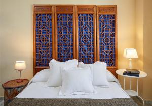1 dormitorio con cama blanca y pared de color azul en El Rico Rincón de Sanlúcar la Mayor, en Sanlúcar la Mayor