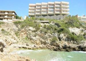 a building on a hill next to a body of water at Cantilmar CALA FONT in Salou