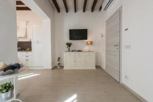 una cucina con armadi bianchi e una TV a parete di Little box house a Firenze