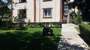 a tree stump sitting in the grass in front of a building at Apartman Izvor in Vrnjačka Banja
