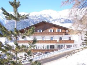 a large building with trees in front of a mountain at Hotel Etschquelle in Resia