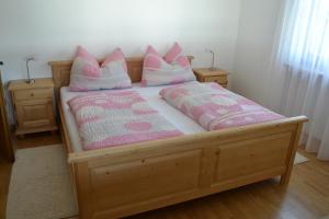 a wooden bed with pink and white pillows on it at Apartment Lukas Huber in Brunico