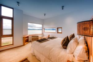 a bedroom with a large bed with windows at Weskar Lodge Hotel in Puerto Natales